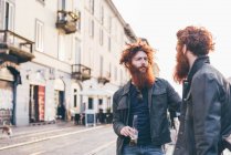 Giovani gemelli hipster maschi con capelli rossi e barbe che parlano per strada — Foto stock
