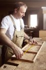 Homem carpinteiro moldura de medição na bancada — Fotografia de Stock