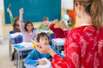 Sobre a visão do ombro do professor da escola primária questionando em sala de aula — Fotografia de Stock