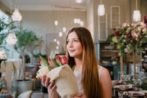 Клієнт в квітковому магазині, тримає купу квітів — стокове фото