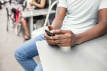 Обрізаний знімок смс молодого чоловіка на смартфоні в міському тротуарному кафе — стокове фото