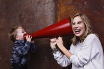 Молодий хлопчик розмовляє мегафоном, жінка тримає мегафон на вухо — стокове фото