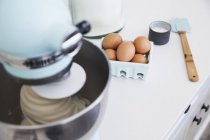 Mezclador de alimentos mezcla de pastel en el mostrador de cocina - foto de stock