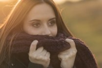 Young woman in rural setting, wearing knitted scarf — Stock Photo