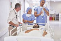 Лікарі, що оточують пацієнта в лікарняному ліжку — стокове фото