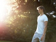 Young man standing outdoors, looking away — Stock Photo