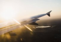 Elevated view of airplane wing over silhouetted landscape at sunset, Finland — Stock Photo