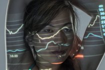 Frau übt vor grauem Hintergrund mit auf Gesicht projizierten Grafiken und Daten — Stockfoto