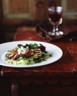 Grilled aubergine and pine nut salad with glass of red wine — Stock Photo