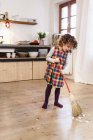 Cute girl sweeping kitchen floor — Stock Photo