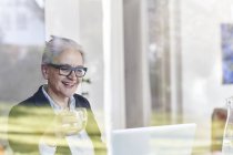 Home window view of senior businesswoman looking at laptop — Stock Photo