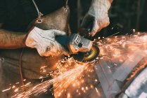 Hands of metalworker grinding copper in forge workshop — Stock Photo