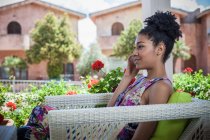 Young woman relaxing on apartment patio talking on smartphone, Costa Rei, Sardinia, Italy — Stock Photo