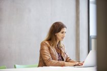 Female designer typing on laptop in design studio — Stock Photo