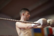 Boxer leaning on ropes of boxing ring — Stock Photo