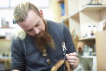 Trabajador masculino en taller de cuero, cosiendo costuras alrededor de una hebilla de cinturón - foto de stock
