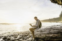 Mann sitzt mit Laptop am Strand im juan de fuca provincial park, vancouver island, britisch columbia, canada — Stockfoto