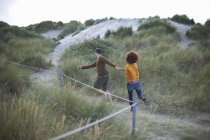 Casal correndo em duna gramada — Fotografia de Stock