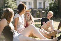 Young man and female friends chatting in park — Stock Photo