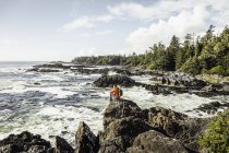 Hombre excursionista mirando hacia el mar desde la costa rocosa, Wild Pacific Trail, Vancouver Island, British Columbia, Canadá - foto de stock