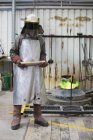 Ouvrier de fonderie tenant un lingot de bronze en fonderie de bronze — Photo de stock