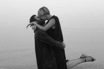 Young couple on beach, hugging and kissing — Stock Photo