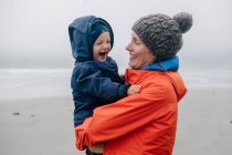 Retrato de la madre sosteniendo al hijo, sonriendo, Long Beach, Isla Vancouver, Columbia Británica, Canadá - foto de stock
