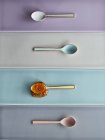 Top view of colorful spoons arranged on multi colored tiles — Stock Photo