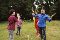 Família brincando ao ar livre, adolescente soprando bolhas na família — Fotografia de Stock