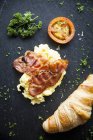 Nature morte de croissant avec tranches de bacon, omelette et tomate — Photo de stock