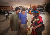 Casal jovem conversando com comerciante de mercado, Praça Jemaa el-Fnaa, Marraquexe, Marrocos — Fotografia de Stock