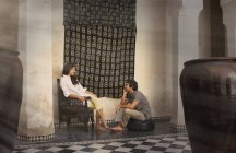 Young couple sitting on chair and pouffe chatting, Marrakesh, Morocco — Stock Photo
