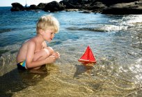 Giovane ragazzo che gioca con una barca a vela giocattolo — Foto stock