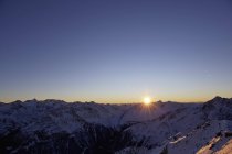 Setting sun over snowcapped mountain range — Stock Photo