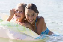 Portrait of two sisters playing with inflatable ring in Lake Seeoner See, Bavaria, Germany — Stock Photo