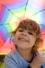 Chica joven bajo paraguas multicolor - foto de stock