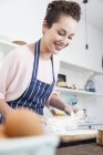 Jeune femme étirant la pâte au comptoir de la cuisine — Photo de stock