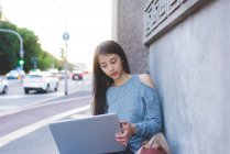 Jovem mulher na calçada usando laptop — Fotografia de Stock