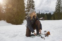 Reife Frau schnürt Schneeschuhe in verschneiter Landschaft, Elmau, Bayern, Deutschland — Stockfoto