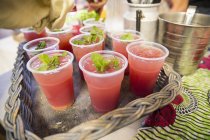 Stall holder garnishing fruit drinks with mint on cooperative food market stall — Stock Photo
