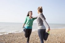 Two women training, standing on one leg on Brighton beach — Stock Photo
