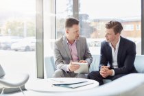 Dos hombres de negocios usando mesa digital en reunión de oficina - foto de stock
