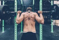 Vue arrière de haltère haltérophilie homme cross trainer dans la salle de gym — Photo de stock