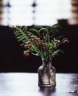 Ferns in old glass bottle, backlit by natural light coming through window — Stock Photo