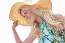 Retrato de una mujer joven sosteniendo el sombrero solar - foto de stock