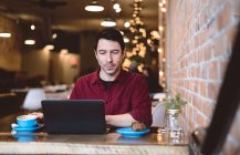 Человек, работающий на ноутбуке в кафе — стоковое фото