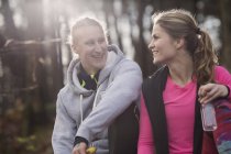Couple wearing sports clothing holding water bottle sitting face to face smiling — Stock Photo