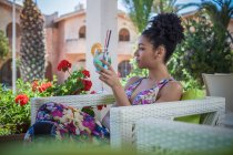 Young woman relaxing on apartment patio drinking cocktail, Costa Rei, Sardinia, Italy — Stock Photo