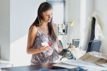 Mujer embarazada mirando muestras de muestras de tela y muestras - foto de stock