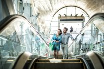 Tourist couple moving up escalator in shopping mall, Dubai, United Arab Emirates — Stock Photo